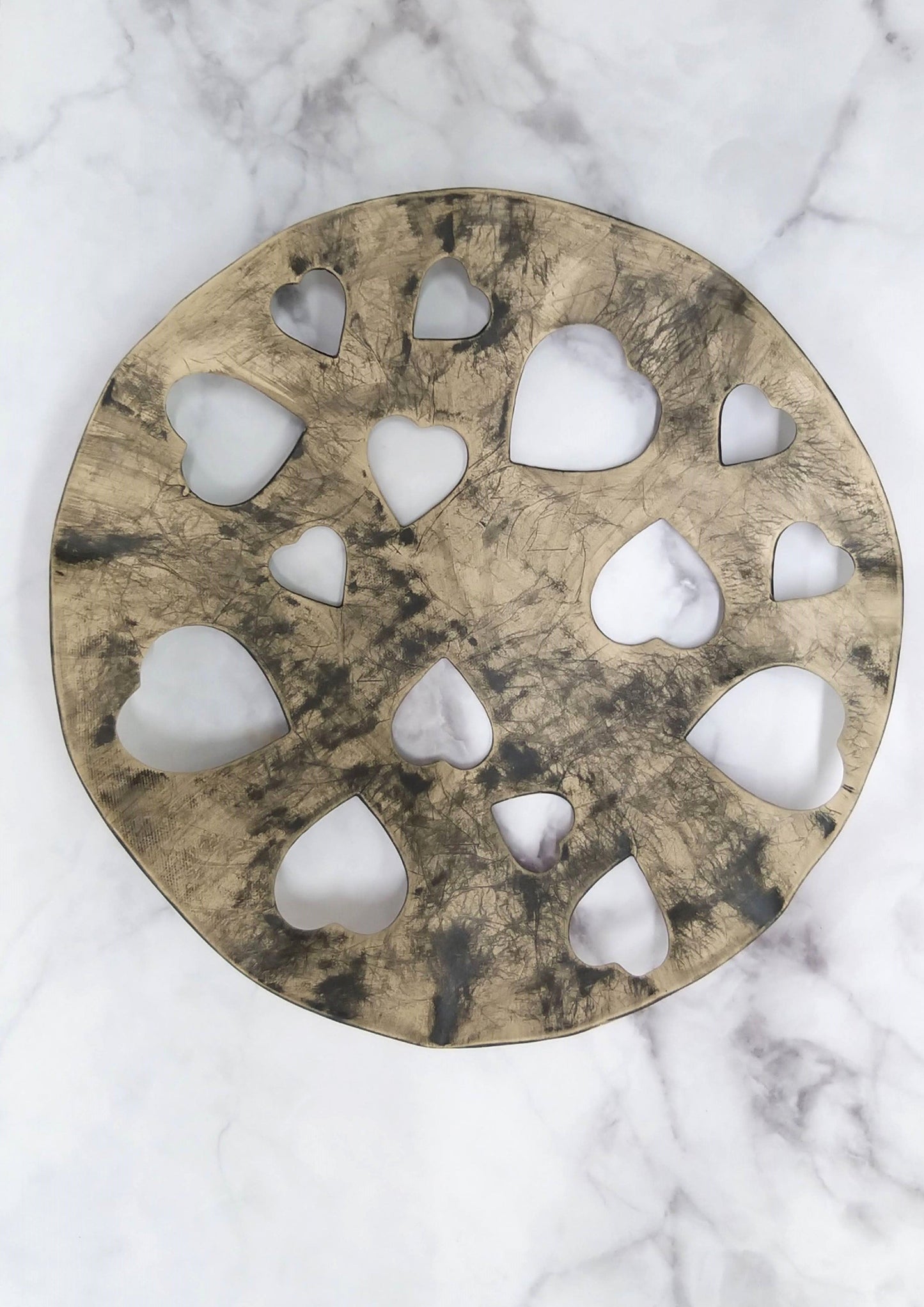 Decorative gray bowl placed in lattice of black heart-shaped holes