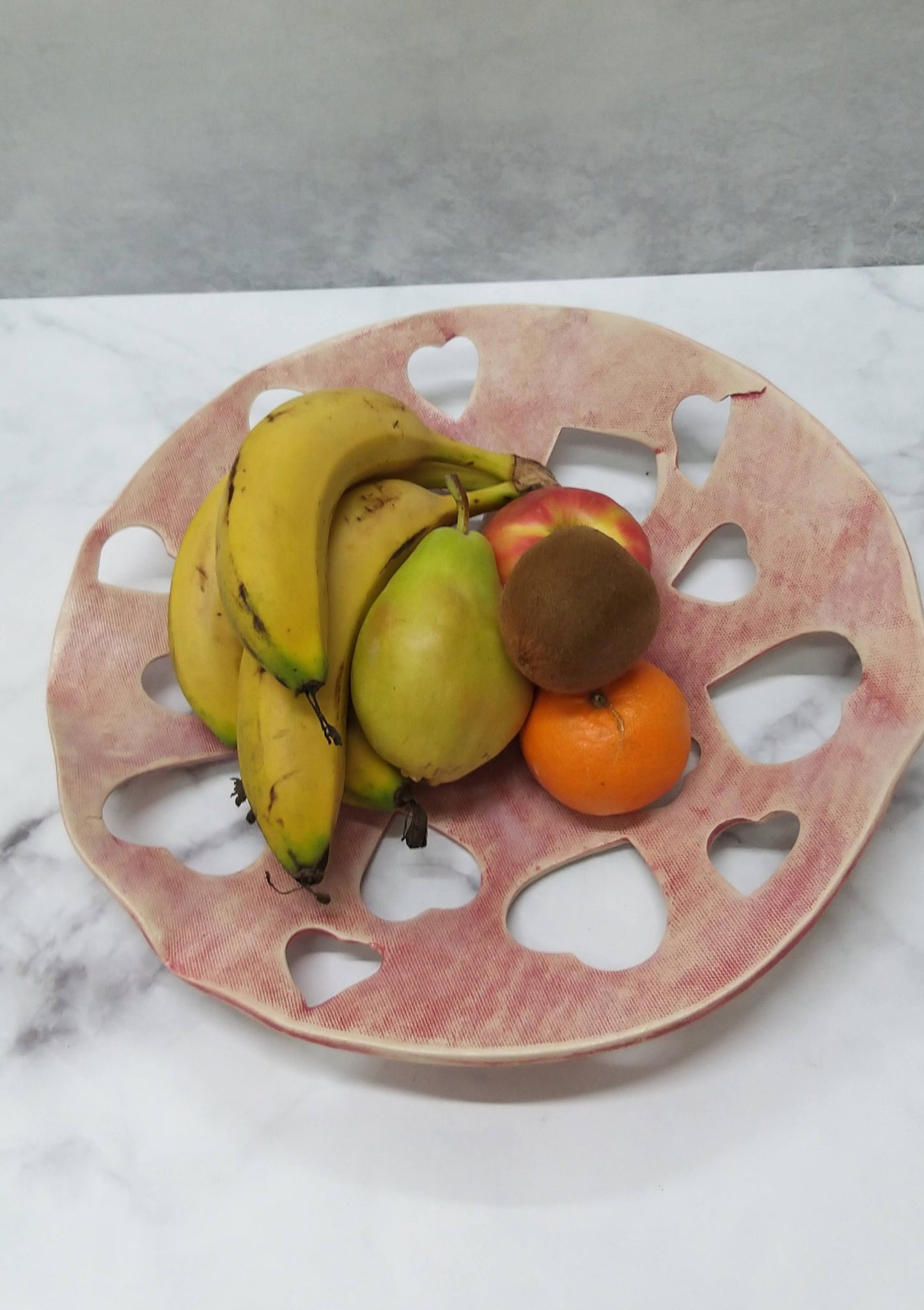 Bright red ceramic Valentine’s Day bowl with fruit and rows of 3cm heart-shaped holes in lattice design