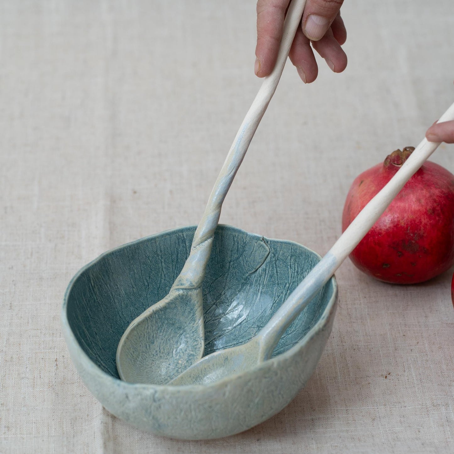 Ceramic bowl with two ceramic spoons on a textured surface
