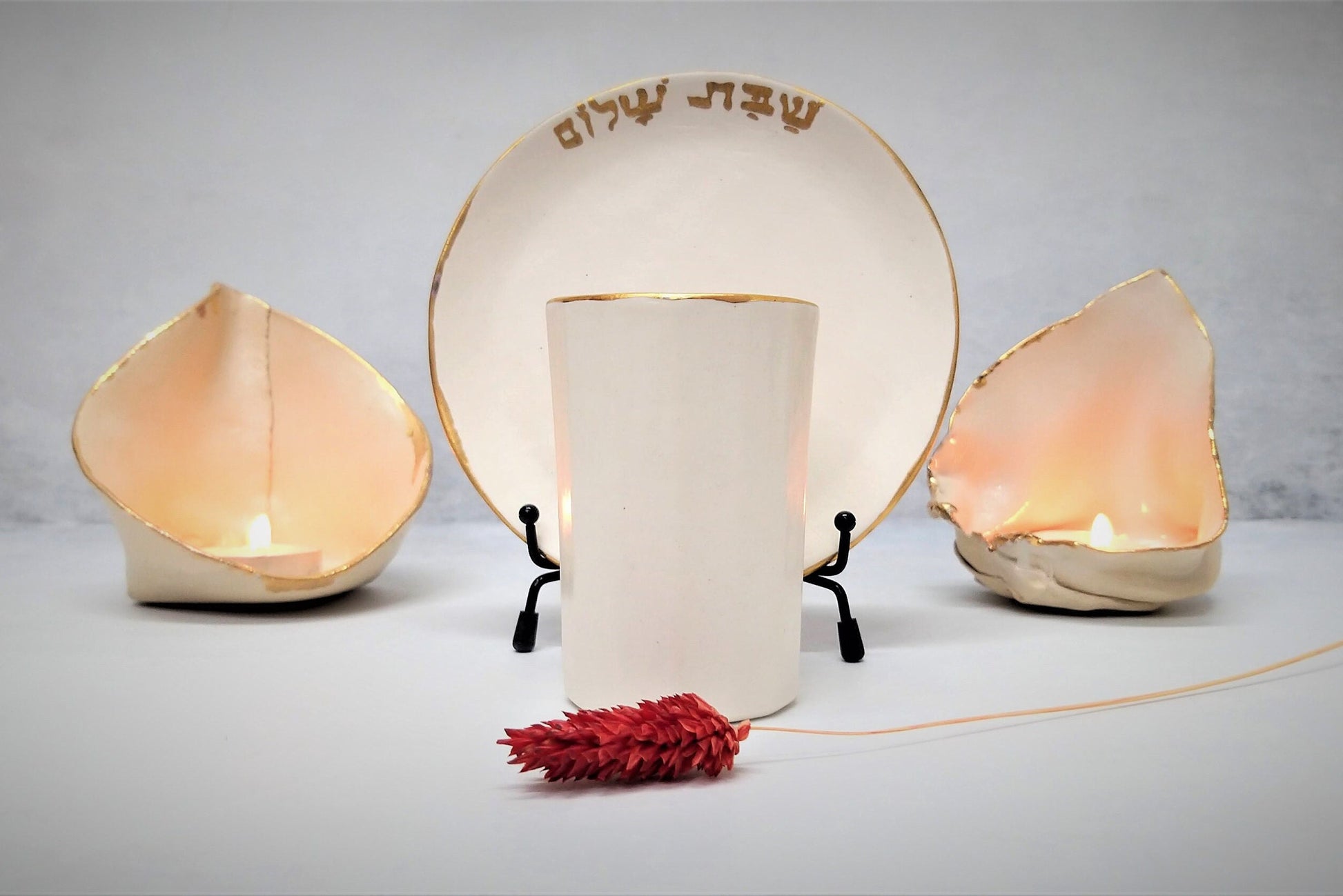 Ceramic kiddush cup and candlesticks with gold rim and Shabbat shalom write in Hebrew