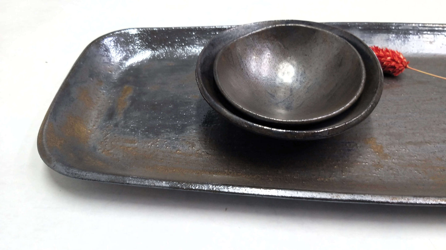 Two small ceramic black bowls on a tray