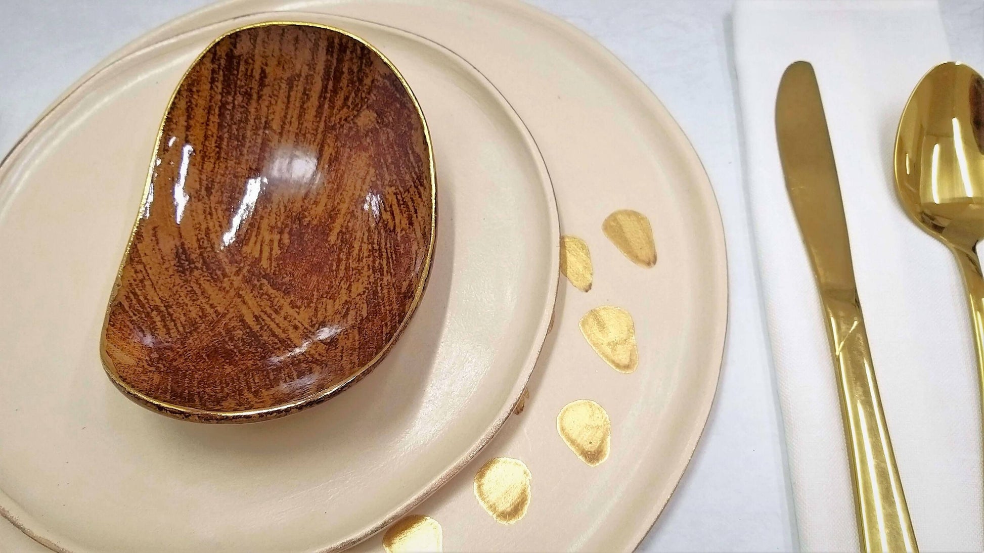 Set of three ceramic plates with 24k gold details on beige background