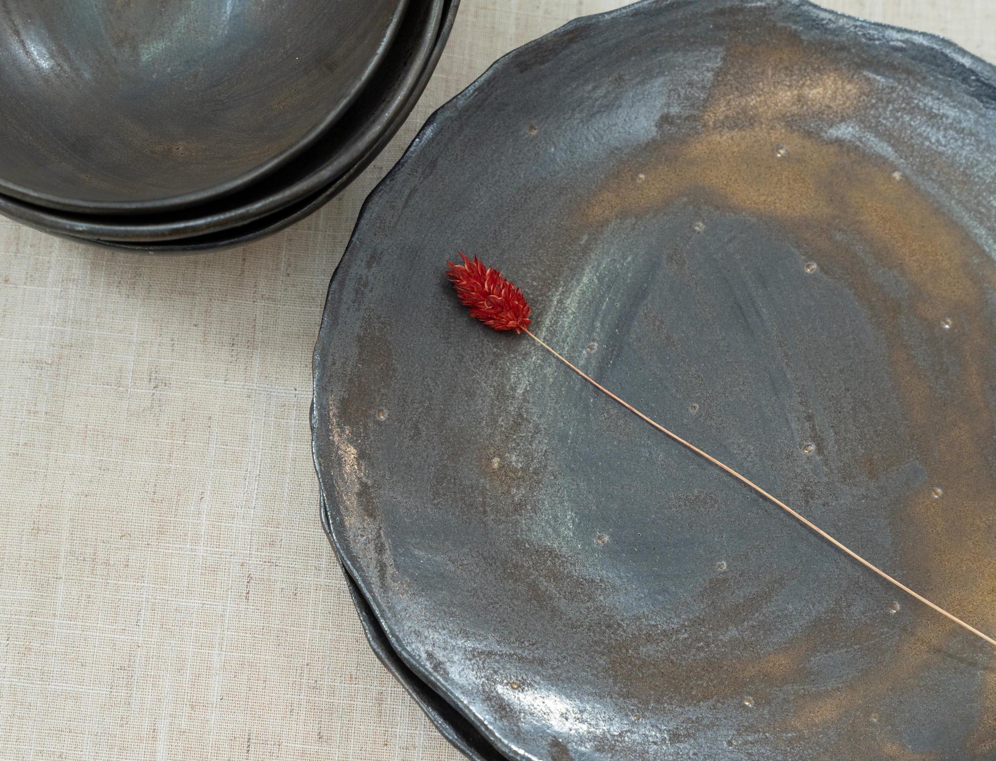 Handmade black ceramic plate next to a rustic bowl