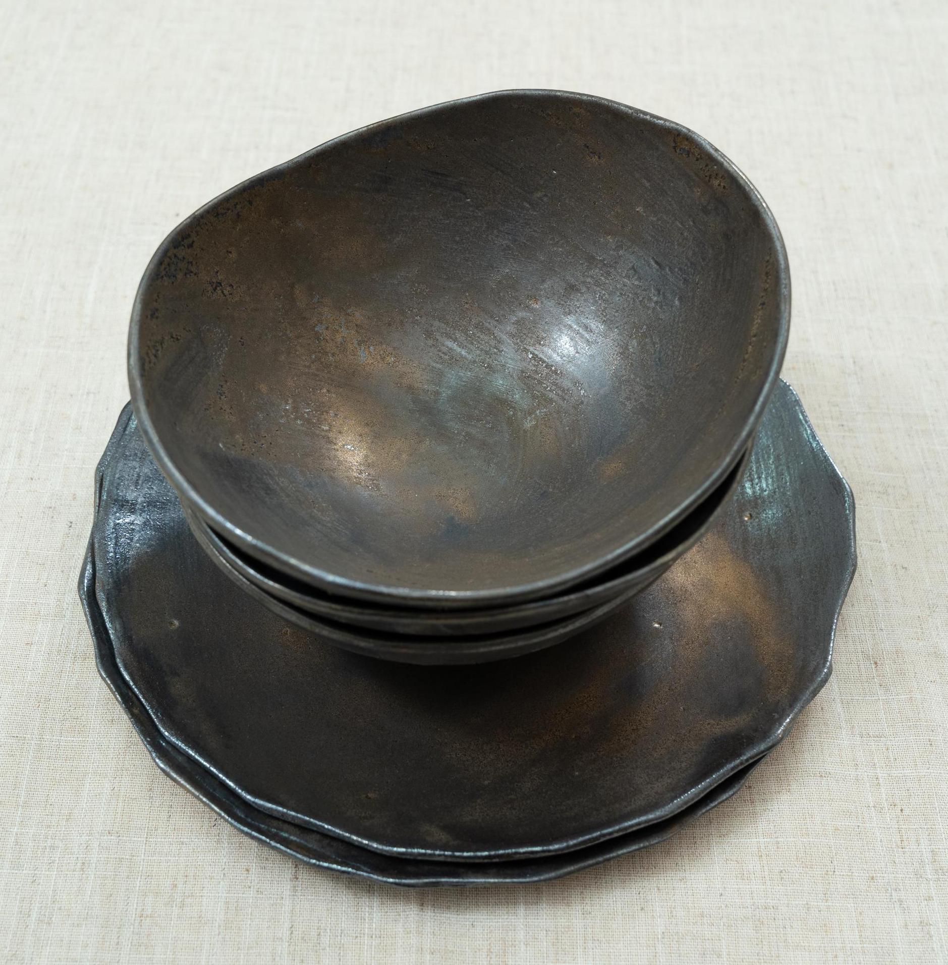 Handmade black ceramic bowls on rustic plates