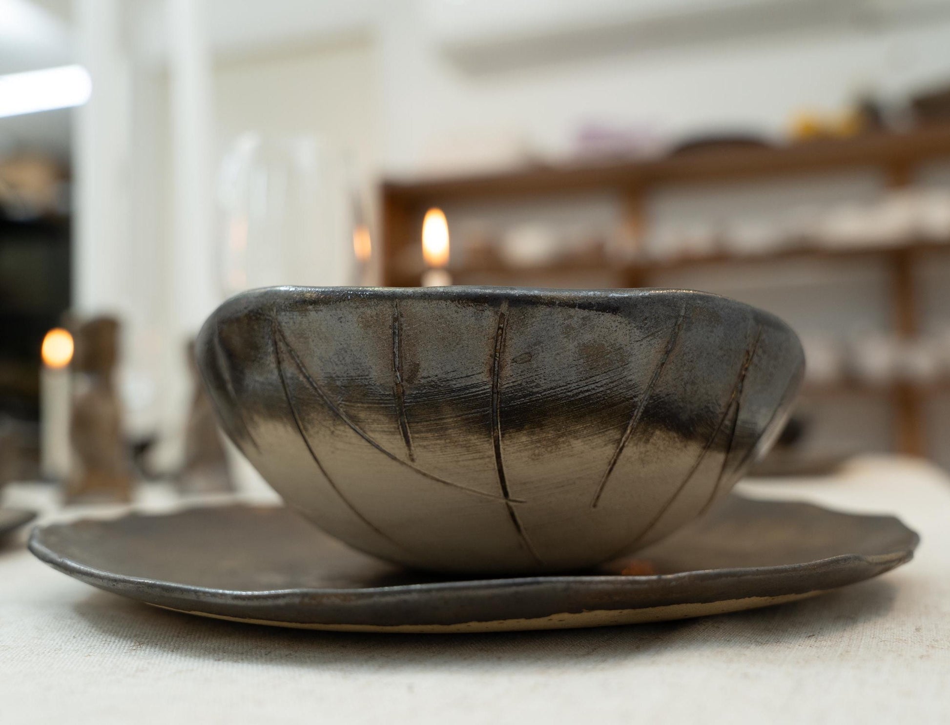 Close-up of handmade black ceramic bowl on rustic plate


