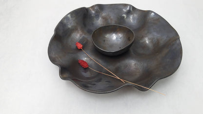 Circular wavering serving tray in black with rust bronze and bluish metallic tones bowl center