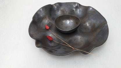 Circular wavering seder plate in black with rust bronze and bluish metallic tones bowl center