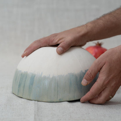 Person holding a ceramic bowl with a gradient design on a neutral background