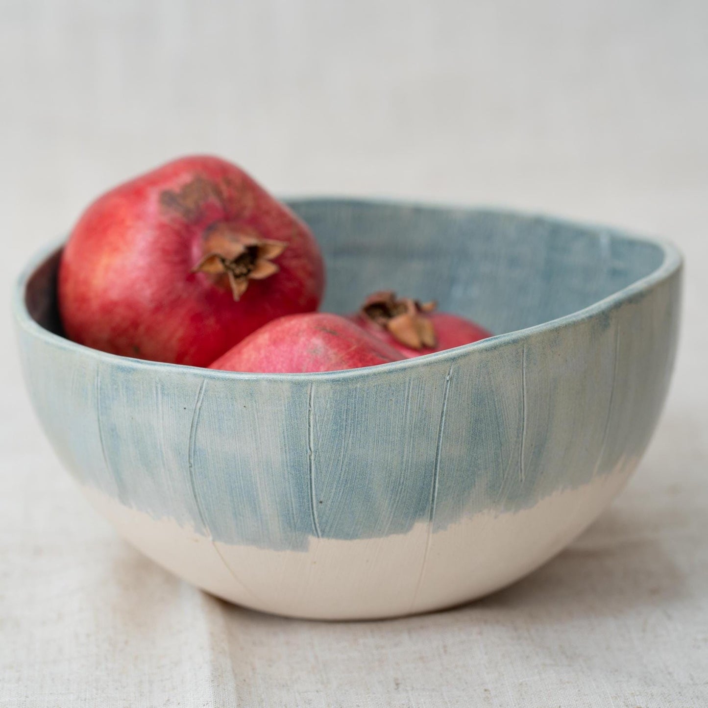 Blue ceramic bowl with pomegranates on a light background