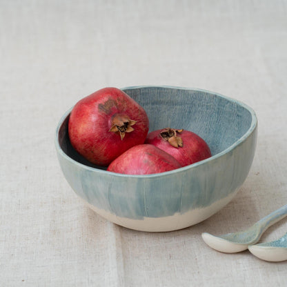 Blue ceramic bowl with pomegranates on a light fabric background