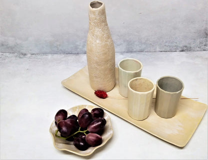 A set of white ceramic cups and bottle